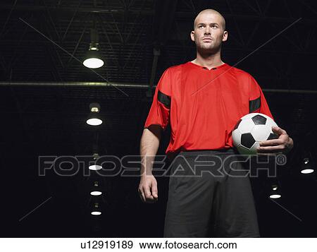 Soccer player holding ball, portrait, low angle view View Large Photo Image Stock Photo - Soccer player holding ball, portrait, low angle view. Fotosearch
