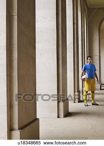 Soccer player holding ball, standing in portico, portrait View Large Photo Image Stock Photography - Soccer player holding ball, standing in portico, portrait. Fotosearch