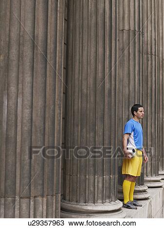 Soccer player holding ball, standing between columns, side view View Large Photo Image Stock Image - Soccer player holding ball, standing between columns, side view. Fotosearch