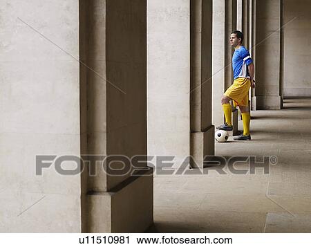 Soccer player holding foot on ball, standing in portico View Large Photo Image Stock Image - Soccer player holding foot on ball, standing in portico. Fotosearch