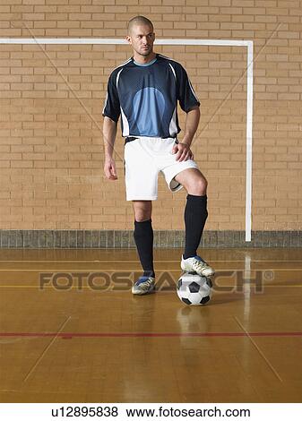Stock Photo - Soccer player standing on ball, portrait. Fotosearch