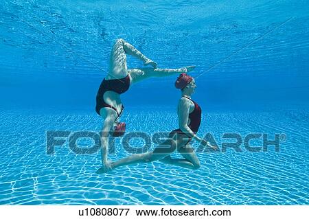 Stock Photo - Synchronised swimmers balance underwater. Fotosearch