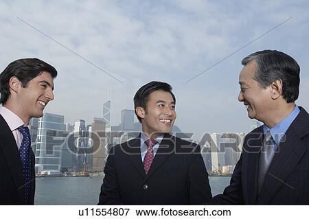 Three business men smiling, office buildings in background View Large Photo Image Stock Photo - Three business men smiling, office buildings in background. Fotosearch