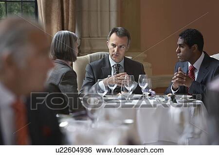 Three business people sitting at restaurant table, talking View Large Photo Image Stock Photograph - Three business people sitting at restaurant table, talking. Fotosearch