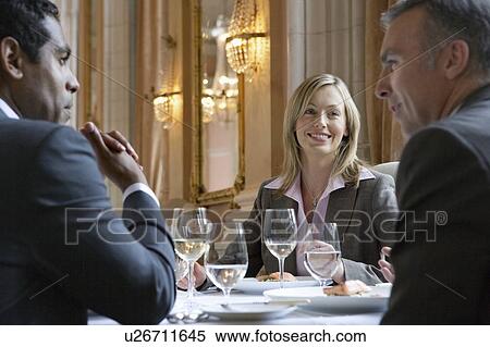 Stock Photography - Three business people sitting at restaurant table, talking. Fotosearch