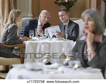 Stock Photo - Three business people sitting at table in restaurant analyzing documents. Fotosearch