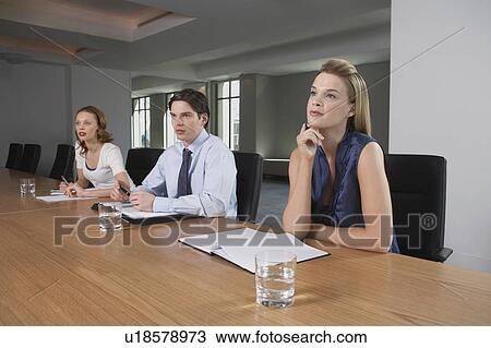 Stock Image - Three businesspeople sitting at conference table. Fotosearch