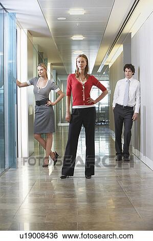 Three businesspeople standing in office corridor, portrait View Large Photo Image Stock Photograph - Three businesspeople standing in office corridor, portrait. Fotosearch
