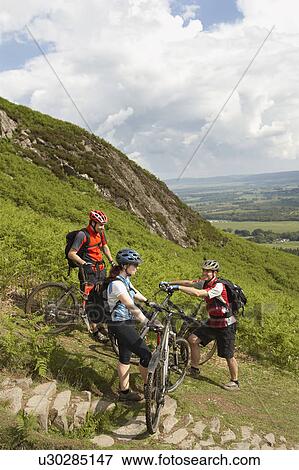 Stock Photo - Three cyclists on hill. Fotosearch