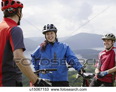 Stock Image - Three cyclists outdoors, smiling. Fotosearch
