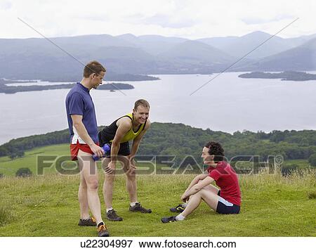 Stock Photo - Three joggers relaxing in countryside. Fotosearch