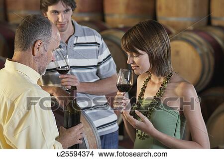 Three people wine-tasting beside wine casks View Large Photo Image Picture - Three people wine-tasting beside wine casks. Fotosearch