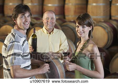 Three people wine-tasting beside wine casks, portrait View Large Photo Image Stock Photo - Three people wine-tasting beside wine casks, portrait. Fotosearch
