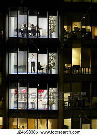 Trapped business man holding up sign in office on floor below meeting, view from building exterior View Large Photo Image Stock Photography - Trapped business man holding up sign in office on floor below meeting, view from building exterior. Fotosearch