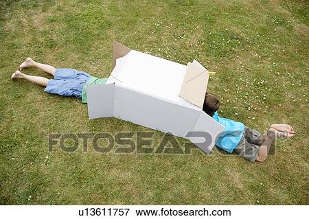Two boys in backyard playing in cardboard box, high angle view View Large Photo Image Stock Photo - Two boys in backyard playing in cardboard box, high angle view. Fotosearch