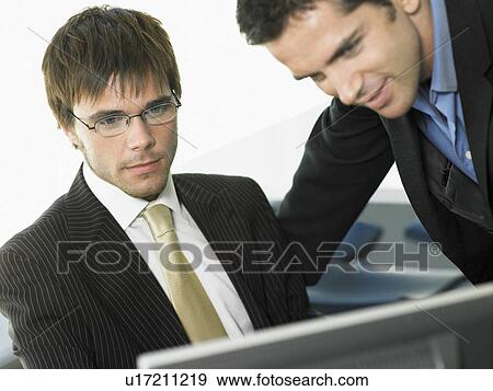 Two businessmen in office looking at computer screen View Large Photo Image Stock Photo - Two businessmen in office looking at computer screen. Fotosearch