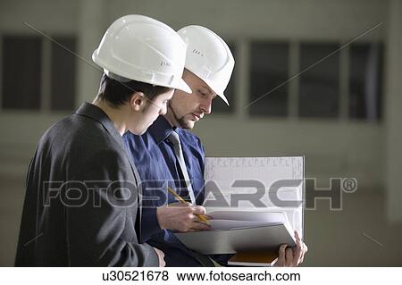 Stock Photo - Two colleagues consult file documentation. Fotosearch