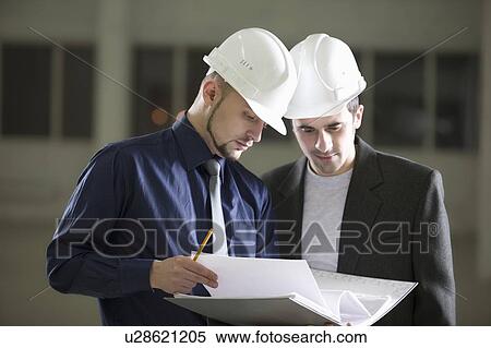 Stock Photography - Two colleagues consult file documentation. Fotosearch