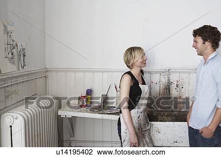 Stock Image - Two college students chatting by sink in art studio. Fotosearch
