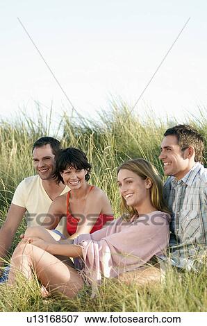 Stock Photo - Two couple sitting and Relaxing in Tall Grass. Fotosearch