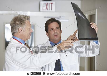 Two doctors looking at x-ray image in hospital View Large Photo Image Stock Photo - Two doctors looking at x-ray image in hospital. Fotosearch