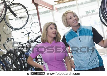 Two female friends look at bikes in a shop View Large Photo Image Stock Image - Two female friends look at bikes in a shop. Fotosearch