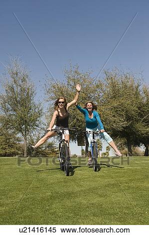 Stock Photography - Two friends cycle downhill one-handed. Fotosearch
