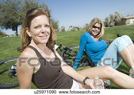 Two friends sit in park with their bikes View Large Photo Image Stock Image - Two friends sit in park with their bikes. Fotosearch