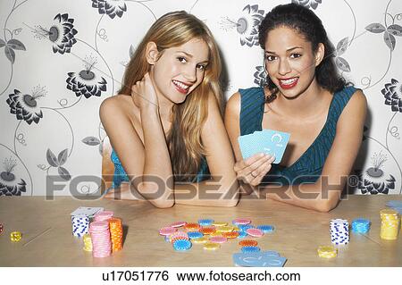 Stock Photograph - Two girls playing cards at table, portrait. Fotosearch
