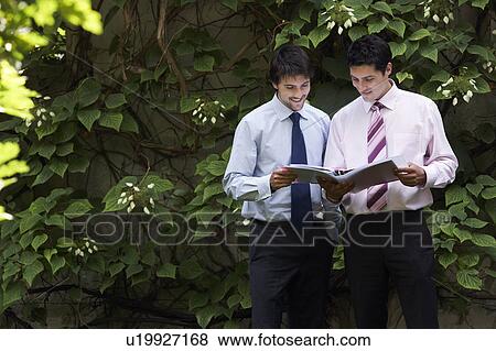 Stock Photo - Two happy businessmen in park examining files. Fotosearch