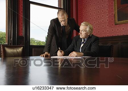 Two Men in Conference Room, one leaning over other View Large Photo Image Stock Photo - Two Men in Conference Room, one leaning over other. Fotosearch