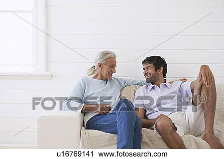Two men sitting on sofa in weather boarded room View Large Photo Image Stock Image - Two men sitting on sofa in weather boarded room. Fotosearch