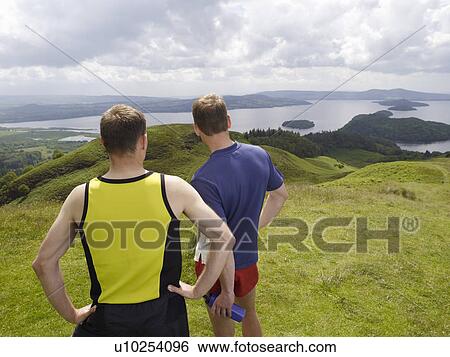 Two men standing on hillside View Large Photo Image Stock Photograph - Two men standing on hillside. Fotosearch