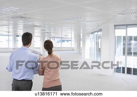 Two office workers looking at plan and empty office space, back view View Large Photo Image Stock Image - Two office workers looking at plan and empty office space, back view. Fotosearch