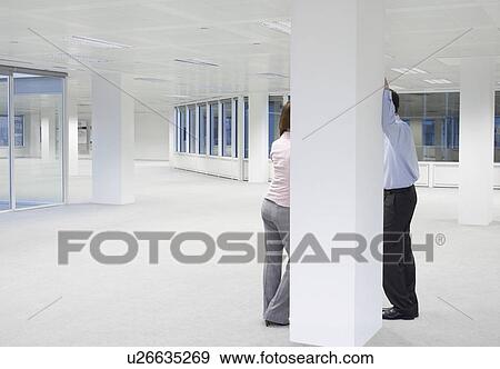 Two office workers talking behind column in empty office space View Large Photo Image Stock Photo - Two office workers talking behind column in empty office space. Fotosearch