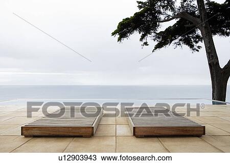 Two sun beds by infinity pool overlooking sea View Large Photo Image Stock Image - Two sun beds by infinity pool overlooking sea. Fotosearch