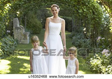 Two young girls and mid adult bride under ivy arches, holding hands, portrait View Large Photo Image Stock Photo - Two young girls and mid adult bride under ivy arches, holding hands, portrait. Fotosearch