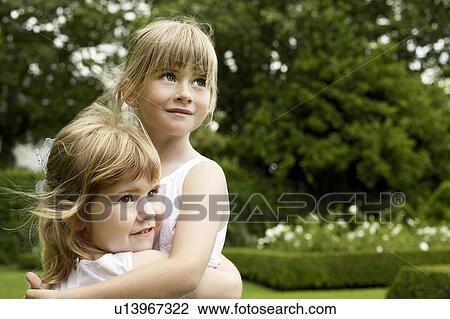 Two young girls in garden, hugging, looking away View Large Photo Image Stock Image - Two young girls in garden, hugging, looking away. Fotosearch