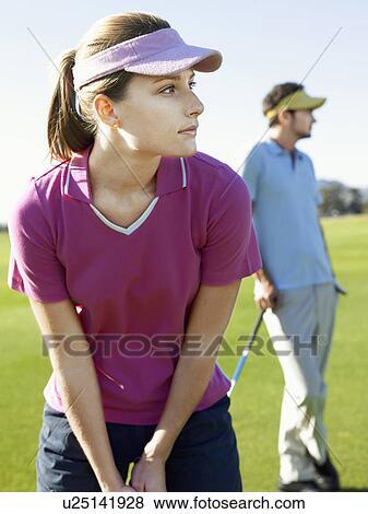 Stock Photo - Two young golfers on course, focus on woman. Fotosearch