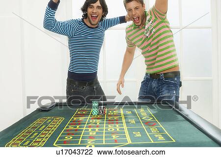 Two young men celebrating on roulette table, portrait View Large Photo Image Stock Image - Two young men celebrating on roulette table, portrait. Fotosearch
