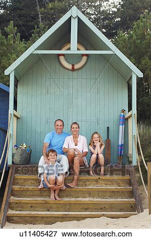 Stock Photo - Vacationing Family sitting in beach hut, portrait. Fotosearch
