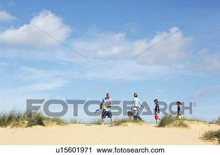 Stock Image - Vacationing Family walking along beach. Fotosearch
