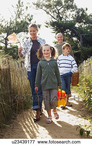 Stock Photo - Vacationing family walking on track to beach. Fotosearch