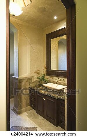 Picture - View through doorway to dark wood bathroom with leather mirror frame. Fotosearch