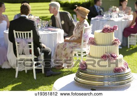 Wedding cake, guests at tables in background View Large Photo Image Stock Image - Wedding cake, guests at tables in background. Fotosearch
