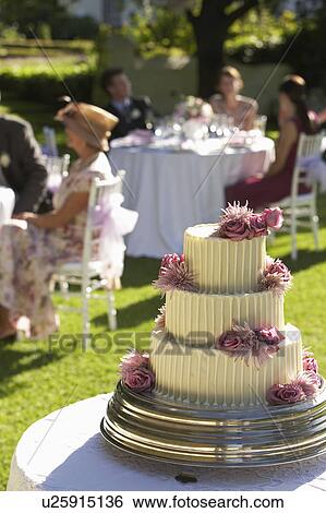 Stock Photograph - Wedding cake, guests at tables in background. Fotosearch