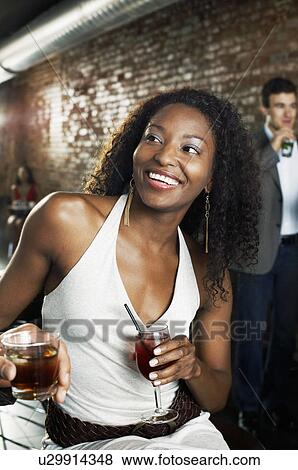 Woman holding cocktail, sitting in bar View Large Photo Image Stock Photo - Woman holding cocktail, sitting in bar. Fotosearch
