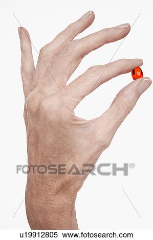 Woman holds red pill between finger and thumb View Large Photo Image Stock Photography - Woman holds red pill between finger and thumb. Fotosearch