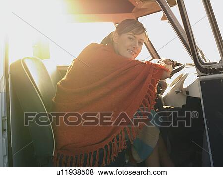 Stock Photo - Woman in poncho sitting in front seat of van. Fotosearch