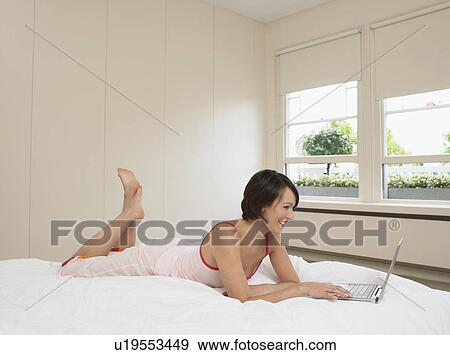 Woman in Pyjamas on bed using laptop View Large Photo Image Stock Photo - Woman in Pyjamas on bed using laptop. Fotosearch